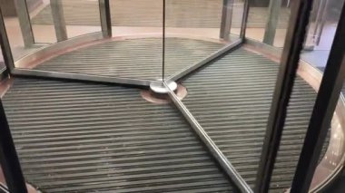 Genç bir kız ve kot ve spor ayakkabı giymiş bir adam otomatik dönen kapıdan binaya girerler..