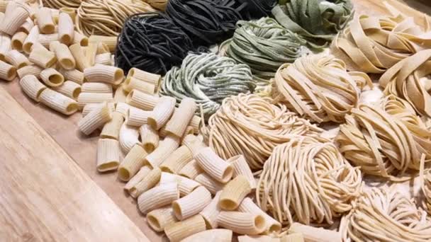 Ein Blick auf verschiedene Arten roher Pasta auf dem Tisch, die mit Weizenmehl bestreut sind. Ernährungskonzept, gesunde Lebensweise. — Stockvideo
