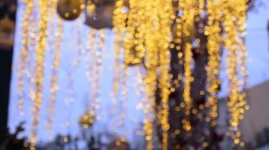 Rüzgarda gelişen bir Noel çelenginin sarı ışıkları, Noel toplarının ve fenerlerin arka planına karşı..
