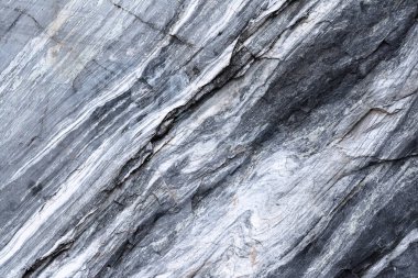 Çatlakları ve düz ve dalgalı çizgiler şeklinde bir deseni olan mermer bir kayanın dokusu çapraz konumdadır. Kavram arkaplan, doku, doğa