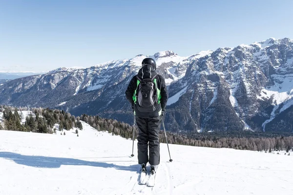Bir adam dağın yamacında karla kaplı Dolomitlerin arka planına karşı duruyor. Spor, manzara, insanlar için kavram