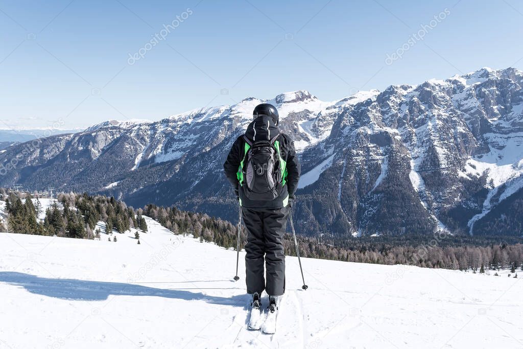 A man stands on the side of a mountain against the backdrop of the snow-capped Dolomites. Concept for sports, landscape, people