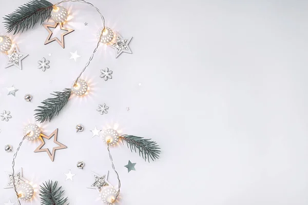 Tahta yıldızların Noel kompozisyonu, beyaz parlak toplardan oluşan bir çelenk, köknar dalları, çanlar ve kar taneleri beyaz arka planda pastel renklerde