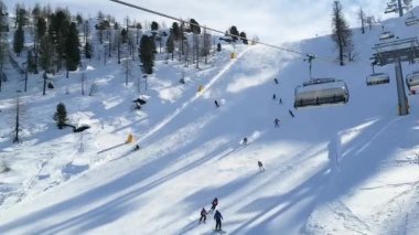 Kayak merkezi Folgarida Marilleva.Folgarida Marilleva.Italya.15.02.2020 Mavi koltuklu vagon manzaralı insanlarla birlikte Dolomitlerin karlı tepelerinin arka planına doğru hareket ediyor.