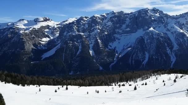 Utsikt över skidbacken längs vilken människor rider mot bakgrund av Dolomiterna i Italien. Begreppet sport, landskap, människor. — Stockvideo