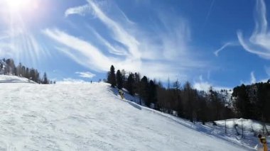 İnsanların gökyüzünün arka planına doğru sürdükleri kayak pistinin en üst görüntüsü bulutlar ve parlak güneşle. İnsanlar, spor, manzara konsepti.