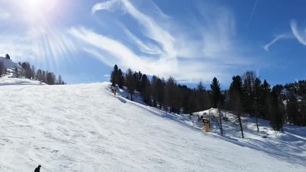 Ovanifrån av skidbacken som människor rider mot bakgrunden av himlen med moln och den ljusa solen. Människor, sport, landskap koncept. — Stockvideo