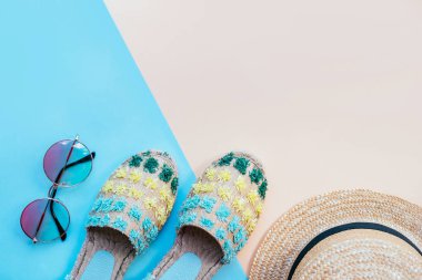 Yaz moda flatlay two-toned mavi ve bej renkli arka plan üzerinde gradyan yuvarlak güneş gözlüğü, hasır şapka ve espadrille sandal ile. Mükemmel kumsal için denizde tatil ayarla. Marina stili.