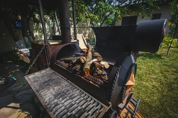 Demirden bir ocakta et yakmak için odun kömür ızgarası. Barbekü hazırlığı. Et için ateş. Barbekü ızgarası altında yakın çekim. Alevler pişmeye hazır. Yakacak odun deposu için fotoğraf