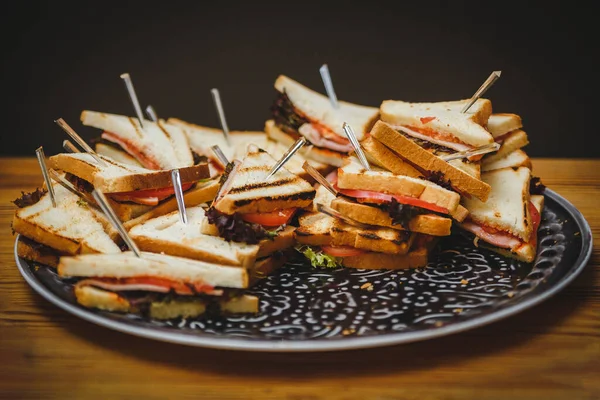 Jambon ve peynirli, taze pişmiş üçgenli büyük tabak. Lokanta, stand-up yemeği ya da ziyafet için fotoğraf. Partideki lezzetli yemekler.