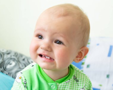 Bir yıl eski bebek üzgün ve ağlayan. Koyun ile ışık Yeşil elbiseli küçük bir çocuk. Yumuşak odak, bokeh