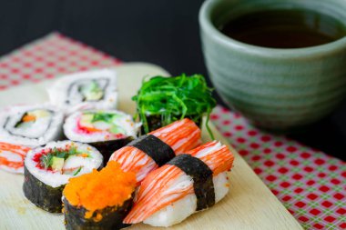 Suşi, çay fincanıyla ahşap tabakta.