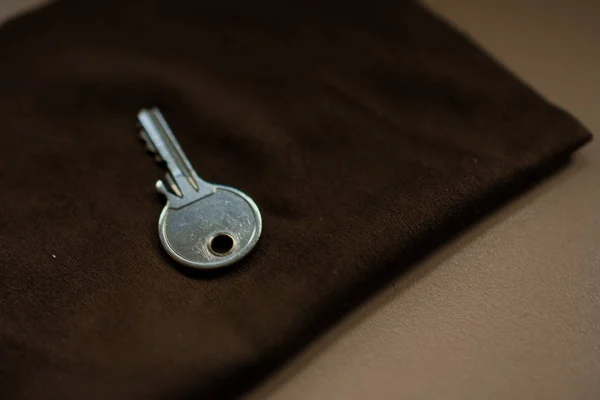 Metalen sleutel op een bruine doek — Stockfoto