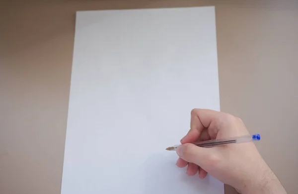 Um jovem está prestes a acabar de escrever num pedaço de papel com uma caneta. — Fotografia de Stock