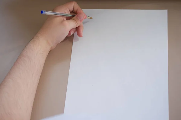 Homem canhoto está prestes a começar a escrever com uma caneta num pedaço de papel em branco — Fotografia de Stock