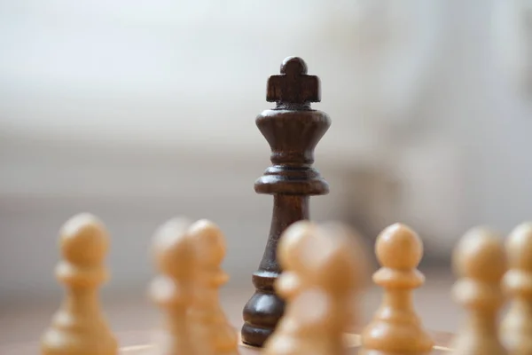 Black king piece is surrounded by white pawns - Conceptual photo of the power of the crowd against the power
