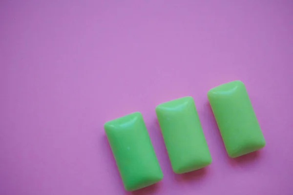 Three green bubble gums on a pink background with copy space on the left
