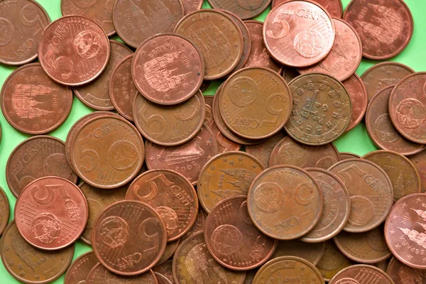 Bunch of five cents of euro coins over a green background