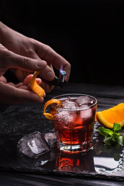 Mezcal Negroni kokteyl. Dumanlı İtalyan aperitivo. Alevli portakal kabuğu.