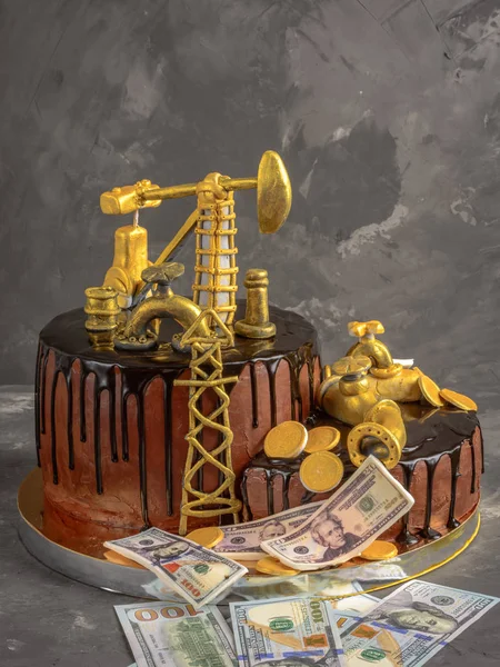 Handmade cake with black chocolate glaze, oil derrick and dollars on a gray concrete background