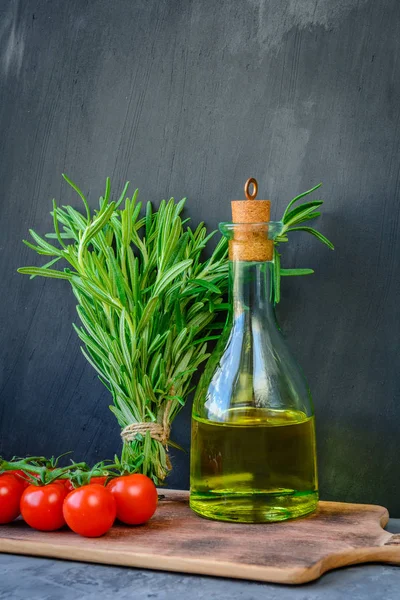 Taze biberiye demet, domates ile bir şişe biberiye yağı veya zeytinyağı üzerinde kesme taş arka plan üzerinde kurulu.