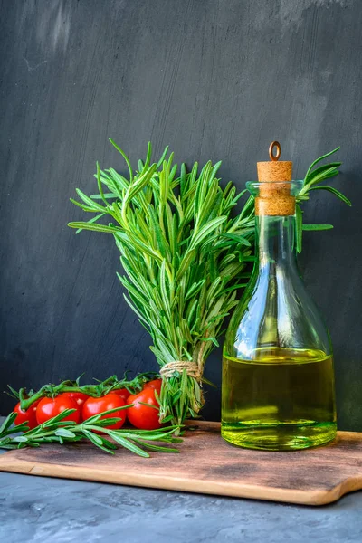 Taze biberiye demet, domates ile bir şişe biberiye yağı veya zeytinyağı üzerinde kesme taş arka plan üzerinde kurulu.