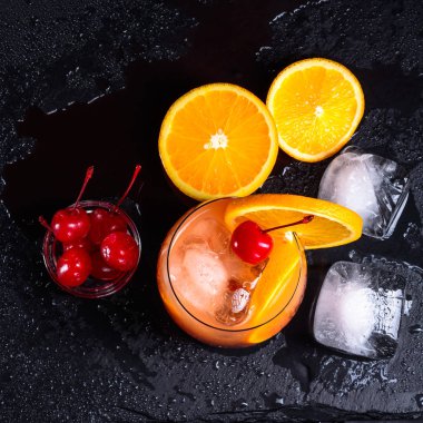 Tekila Sunrise kokteyli, portakal, Ice cube ve ıslak bir siyah arduvaz tepsi maraschino kirazı.