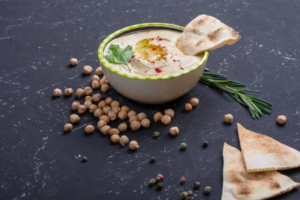 Hummus fatto in casa, fagioli di ceci, rosmarino con pita sul tavolo di pietra nera. Medio Oriente cucina tradizionale e autentica araba . — Foto Stock