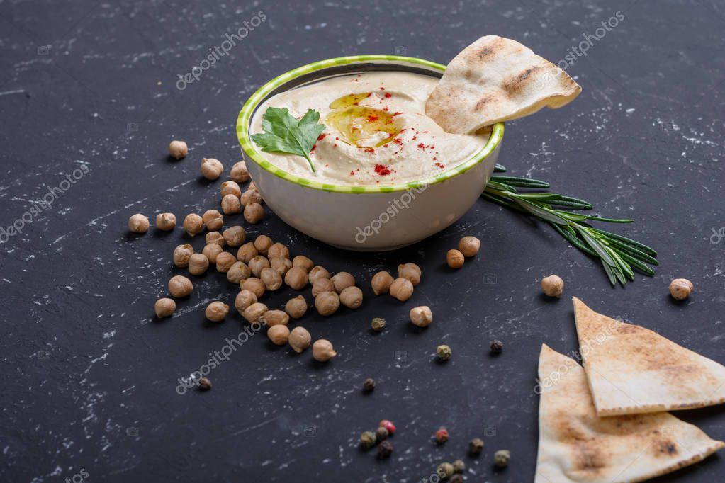 Hummus casero, garbanzos, romero con pita sobre mesa de piedra negra