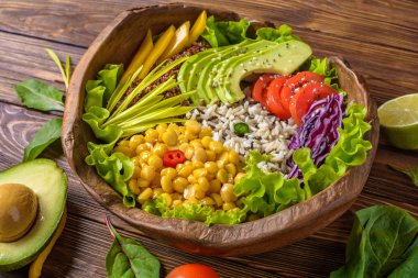 Nohut, avokado, yabani pirinç, Quinoa tohumu, biber, domates, yeşillik, lahana, kahverengi yanmış ahşap arka plan üzerinde marul ile Buda kase. Sağlıklı vegan gıda.