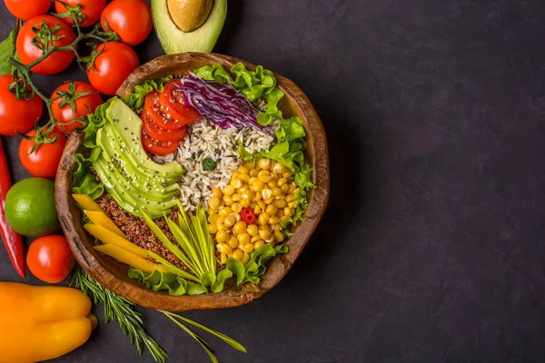 Wooden bowl with chickpea, avocado, wild rice, quinoa, tomatoes, greens, cabbage, lettuce on dark stone background. Vegetarian superfood. Top view with copy space. 로열티 프리 스톡 이미지