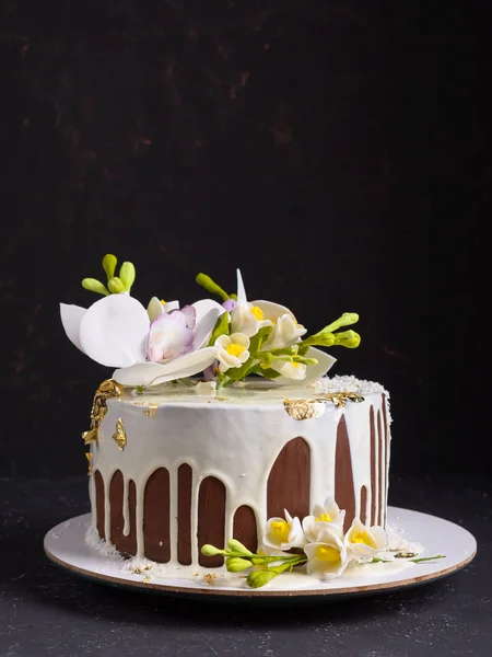 꽃으로 장식 된 초콜릿 케이크와 검은 돌 배경에 흰색 장식을 부어. 로열티 프리 스톡 사진