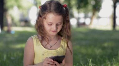 Parkta kız bir akıllı telefon kullanarak sosyal ağlarda arkadaşlarınızla iletişim kurar. Cep telefonu kullanarak sohbet gülümseyen Genç, mesaj yazarak, onu Gadget üzerinde fotoğraf veya diğer ilginç içerik görüntülemek.