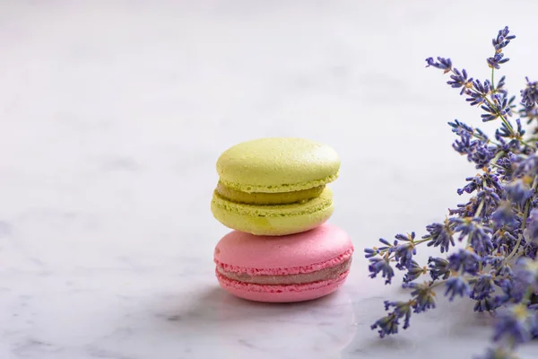 Zwei Macarons und ein Bund Lavendel auf weißem Naturmarmortisch — Stockfoto