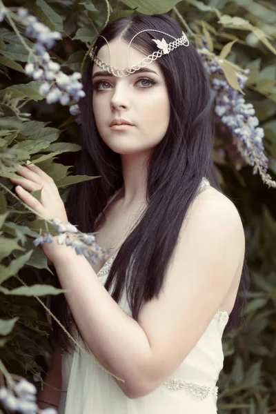 Portrait of young woman wearing silver headpiece at botanical garden