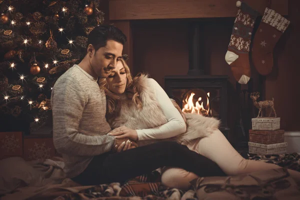 Loving couple by a roaring log fire at Christmas