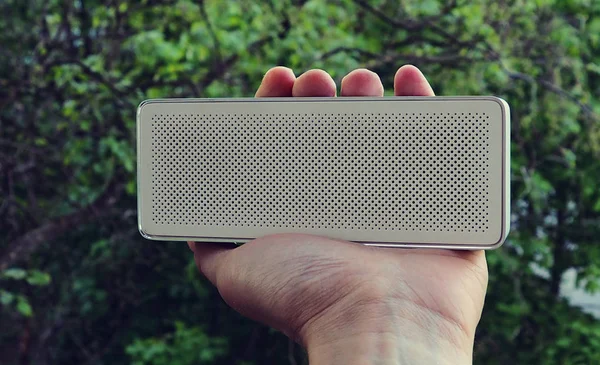 Ağaç arka plan üzerinde elinde Bluetooth sözcü