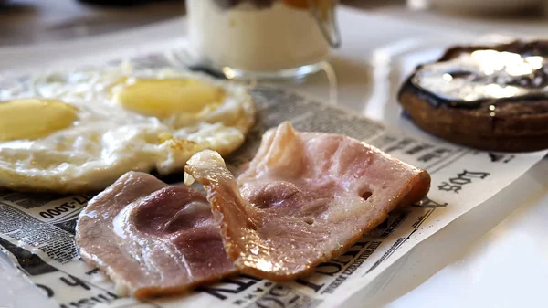 Breakfast with fried eggs, bacon, pancake and yogurt on white plate. Side view of restaurant breakfast. Delicious and nourishing breakfast.