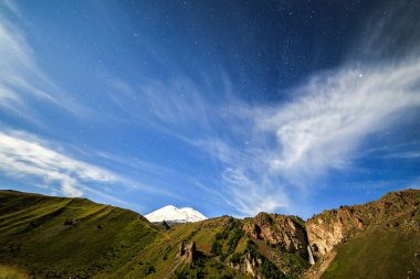 Yıldızlar ve bulutlar Elbruz Dağı üzerinde. Gece manzarası. Rusya