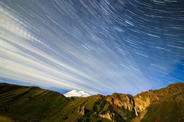 Yıldız solma çizgiler ve bulutlar üzerinde Elbruz Dağı çizme. Gece manzarası. Rusya. Yıldızlardan gelen bir çizgi şeklinde iz