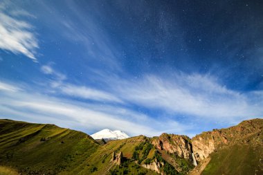 Yıldızlar ve bulutlar Elbruz Dağı üzerinde. Gece manzarası. Rusya