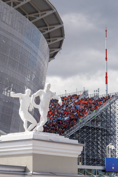 Россия, Екатеринбург - 15 июня 2018 года: Скульптуры футболистов на фоне заполненных трибун Египта - Уругвая матча центрального стадиона Екатеринбурга. Чемпионат мира по футболу 2018 в России
