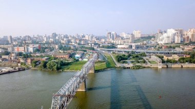 Elektrikli tren Ob nehir geçiyor. Novosibirsk ilk demiryolu köprüsü. Novosibirsk şehir panoraması. Rusya'dan Dron  