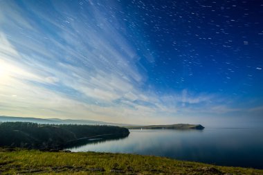 Russia, Lake Baikal, Olkhon Island, Clouds and Stars on the Small Sea Bay. Cape Sagan-Khushun clipart