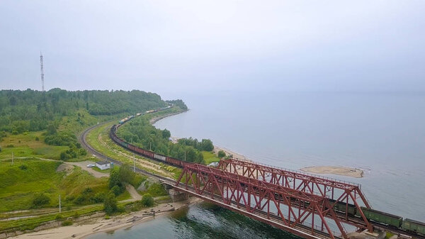 Россия, Байкал - 2 августа 2018 года: Транссибирская железная дорога, побережье озера Байкал. Движение поездов по железному мосту через реку, впадающую в Байкал, из Дрона
  