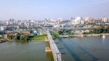 Elektrikli tren Ob nehir geçiyor. Novosibirsk ilk demiryolu köprüsü. Novosibirsk şehir panoraması. Rusya'dan Dron  