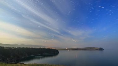 Rusya, Baykal Gölü, Olkhon Adası, bulutlar ve küçük deniz Bay mehtaplı bir gecede yıldızlara. Yıldızlardan, yankı bulutların arasından kısa solma izler. Video. UltraHD (4k)
