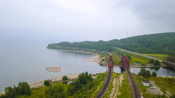 Trans-Siberian Railway, the coast of Lake Baikal. Movement of trains on the iron bridge across the river flowing into Baikal. Russia, From Drone