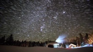 Kışın yıldızlı gökyüzü arka planda küçük ev. İzleri çizgiler şeklinde bırakın. Video. UltraHD (4k)
