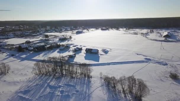 太陽に対して雪で覆われた村や野原の上空を飛んでいます ドローンのプロペラが表示されます 夜の時間 冬の快晴 ビデオ Ultrahd — ストック動画
